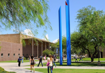 An exterior photo of the Paradise Valley Community College campus with students walking across the lawn