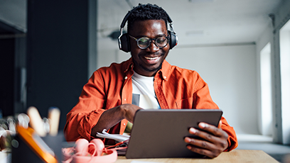 Male student wearing headphones working an a tablet 