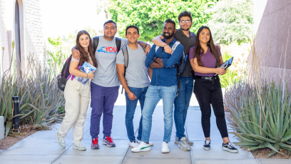 Six college students standing together  outside wearing backpacks and holding books
