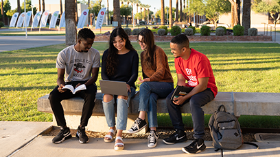 Four GCC students sitting outside on a bench