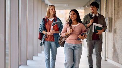 A stock photo of three college students walking down a hallway