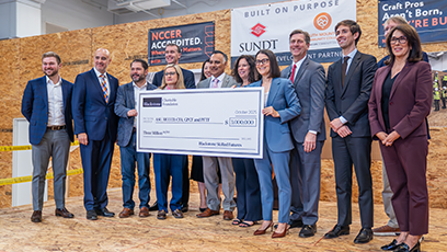 Image of elected officials, college administrators, and Blackstone representatives holding a large check
