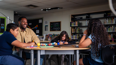 Gabriel Relf sitting at a table with three students