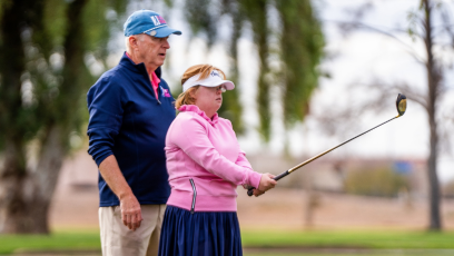 Joe Bockerstette standing bending his daughter Amy Bockerstette who is holding a golf club.
