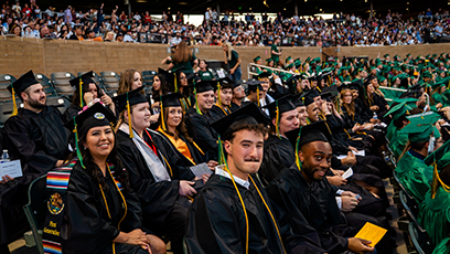 A large group of Maricopa Community College' bachelor's degree graduates wearing caps and gowns seated in an auditorium.