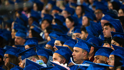 Students seated at graduation wearing blue cap and gowns