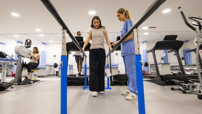Physical Therapy facility with female using walking station with nurse in attendance.