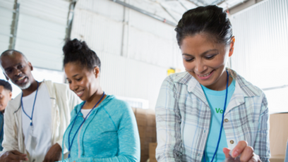 Image of two women and one man volunteering and packing a food box