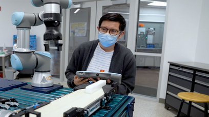 Image of man in a mask working on collaborative robots.