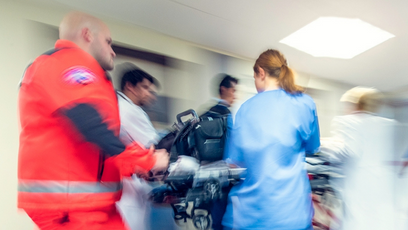 A blurred image of EMTs and medical professionals transport a patient in a hospital