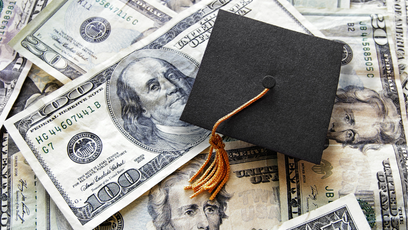 Image of money with a graduation cap laying on top of the money