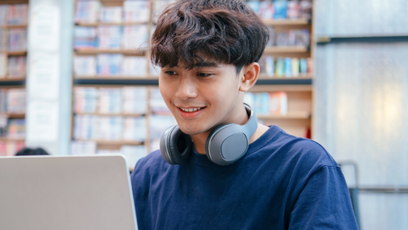 A student wearing a blue T-shirt using a laptop 