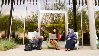 Three students sitting outside working on their laptops