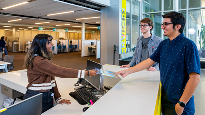Image of a community college employee hand a brochure to a students