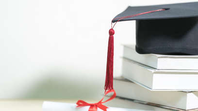 Image of a stack of books with a graduation cap on top