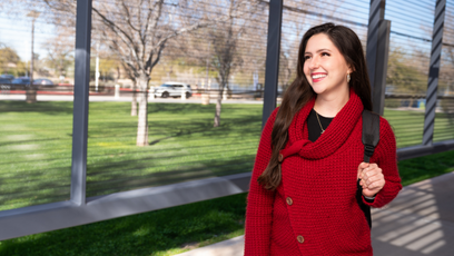 Image of a smiling woman walking outside wearing a red sweater