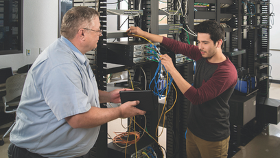 Image of a teacher working with a student on computer servers