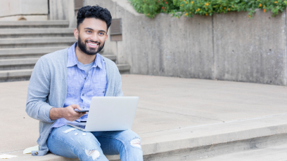An image of a man sitting on steps using a laptop