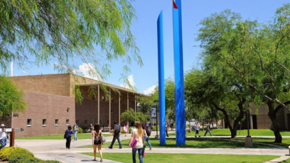 An exterior photo of the Paradise Valley Community College campus with students walking across the lawn