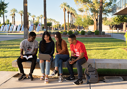Four GCC students sitting outside on a bench