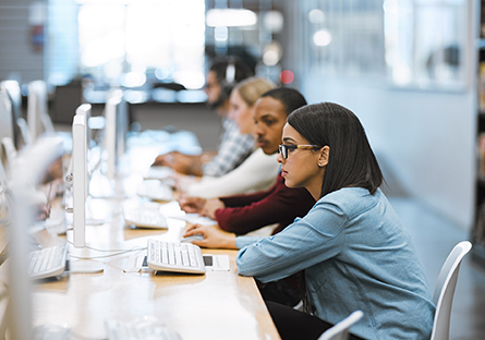 A stock photo of colleges students using computers.