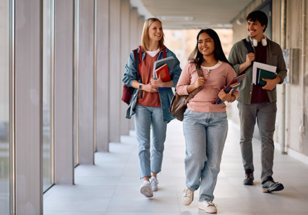 A stock photo of three college students walking down a hallway