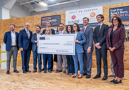 Image of elected officials, college administrators, and Blackstone representatives holding a large check