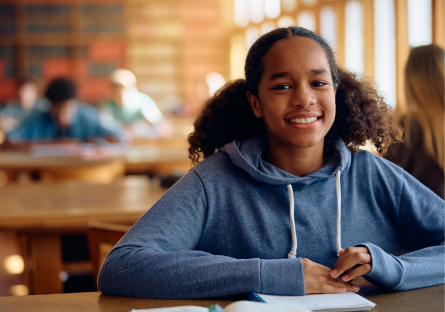 A smiling African American female high school student wearing a light blue hoodie