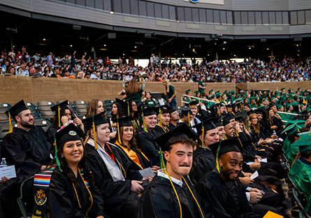 A large group of Maricopa Community College' bachelor's degree graduates wearing caps and gowns seated in an auditorium.