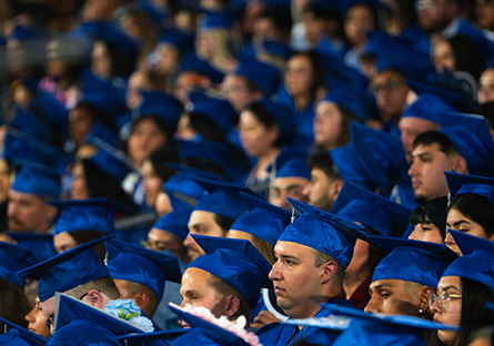 Students seated at graduation wearing blue cap and gowns