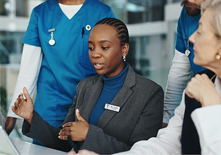 Female seated at a table discussing with nursing staff surrounding her.