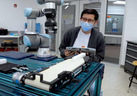 Image of man in a mask working on collaborative robots.