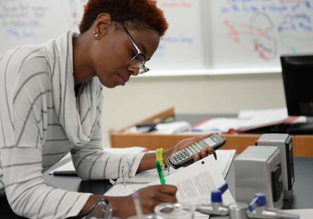 A woman working on an assignment holding a calculator