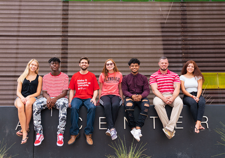 Image of seven students sitting outside of a building on GCC campus
