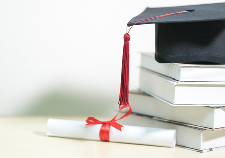 A stack of books with a graduation cap on top