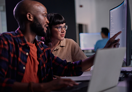 A man and woman sitting side by side looking at a computer monitor