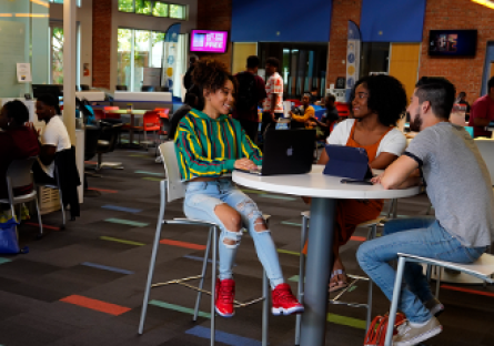 A group of college students sitting at a high top table engaged in conversation