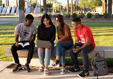 Four GCC students sitting outside on a bench
