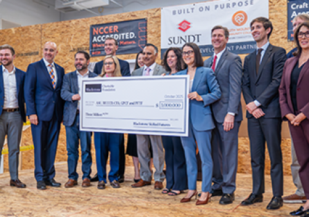 Image of elected officials, college administrators, and Blackstone representatives holding a large check