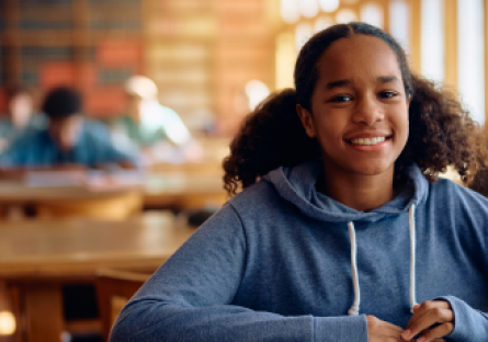 A smiling African American female high school student wearing a light blue hoodie