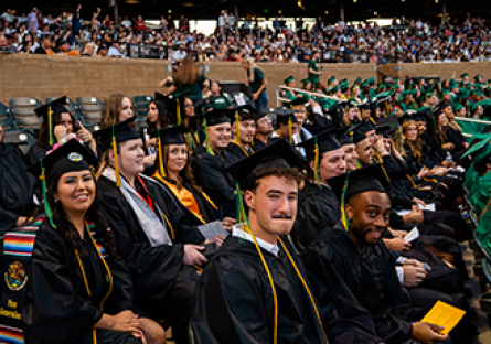 A large group of Maricopa Community College' bachelor's degree graduates wearing caps and gowns seated in an auditorium.