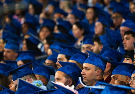 Students seated at graduation wearing blue cap and gowns
