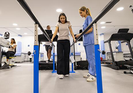 Physical Therapy facility with female using walking station with nurse in attendance.