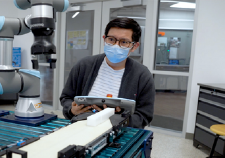 Image of man in a mask working on collaborative robots.