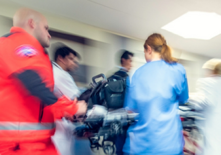 A blurred image of EMTs and medical professionals transport a patient in a hospital