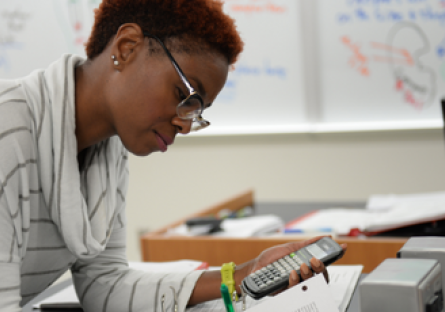 A woman working on an assignment holding a calculator