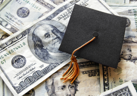 Image of money with a graduation cap laying on top of the money