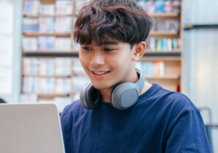 A student wearing a blue T-shirt using a laptop 