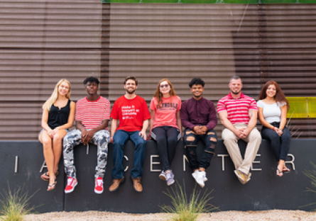Image of seven students sitting outside of a building on GCC campus