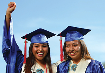 Image of two  female Native American graduates wearing cap and gown